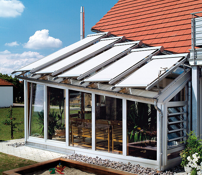 Wintergarten mit aussenliegender Dachbeschattung durch separat geführte weisse Markisentücher.