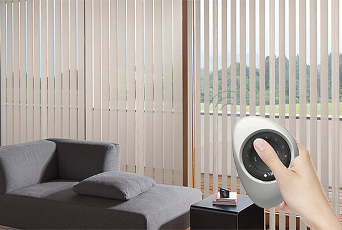 Wohnzimmer mit beigen Lamellenvorhängen und einer Hand, die eine Fernbedienung zur Steuerung des Sonnenschutzes hält