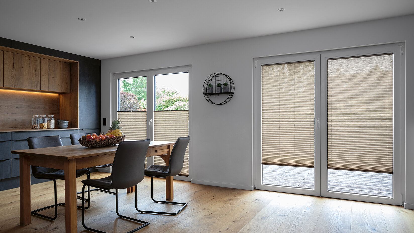 Beiges Plissee als Sichtschutz in heller Wohnküche mit Holzboden und Essbereich.
