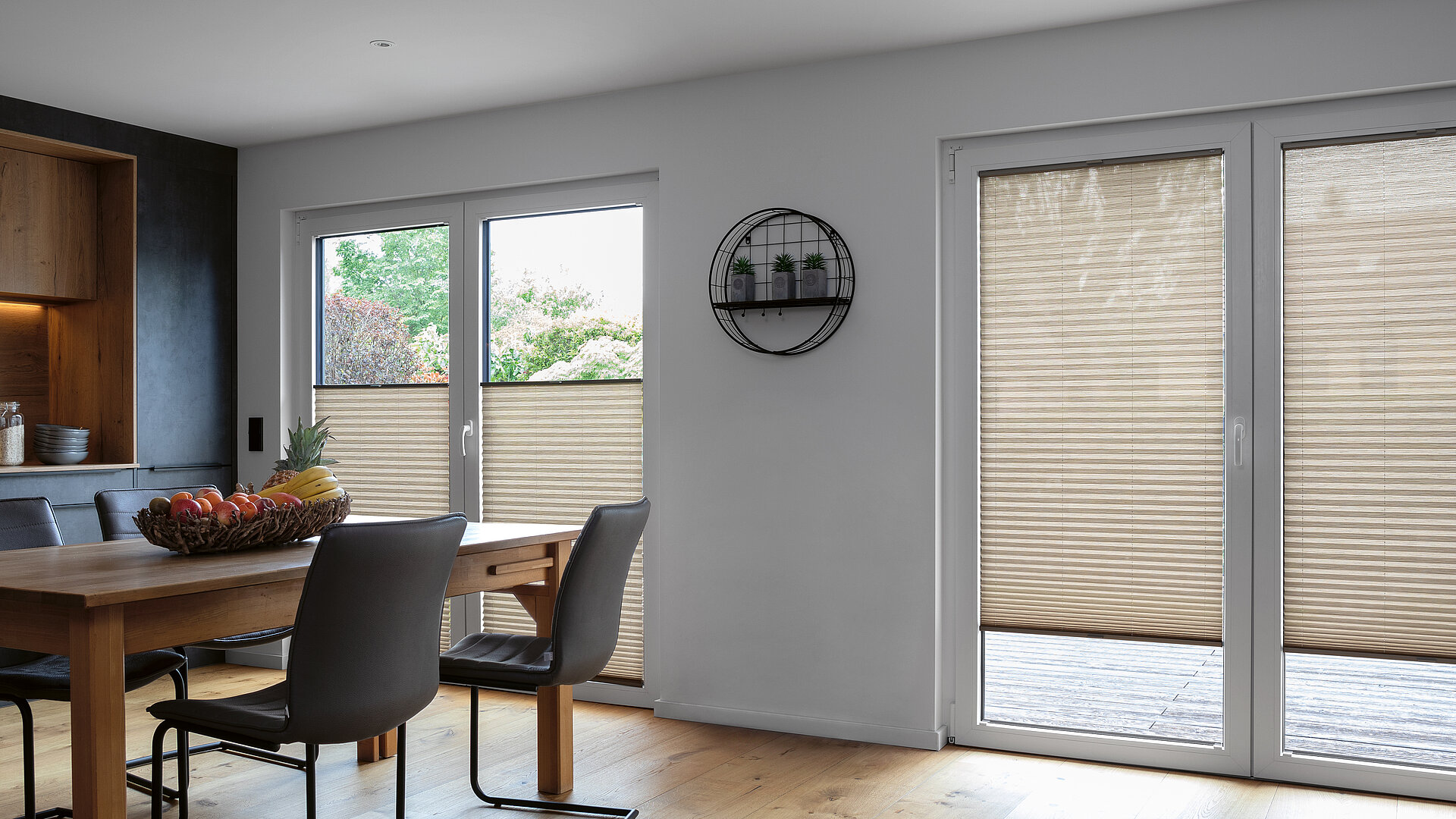 Beiges Plissee als Sichtschutz in heller Wohnküche mit Holzboden und Essbereich.