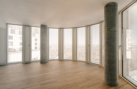 Innenraum mit bodentiefen Fenstern und vertikalen MHZ-Metallbehängen Senn vor einer Panorama-Aussicht.