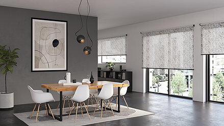 Urbanes Esszimmer mit floralen lichtdurchlässigen Rollos vor grossen Fenstern. Blättermuster in feiner Struktur, helle Möbel und moderne Kunst an der Wand.