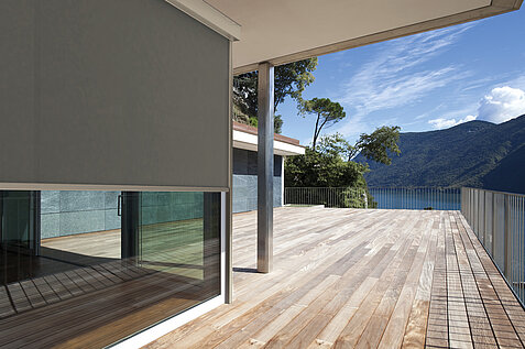 Blend- und Sonnenschutz durch graue Senkrechtmarkise an den Türen und Fenster