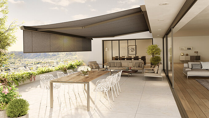 Anthrazitfarbene Markise mit Volant an der vorderen Kassette über stilvoll möblierter Terrasse.