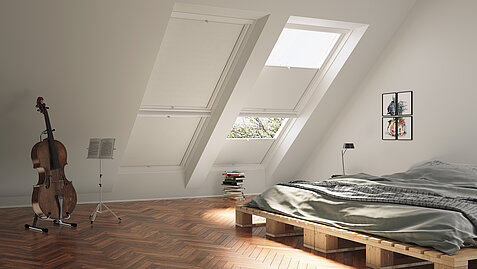 Schlafzimmer mit Dachschrägen und weissen Wabenplissees an zwei grossen Dachfenstern.