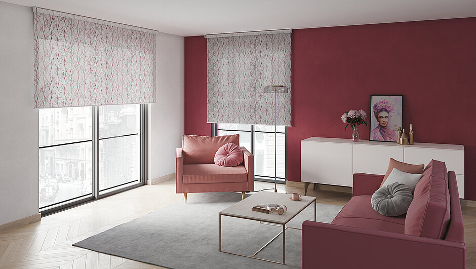Modernes Wohnzimmer mit zwei grossen Fenstern, ausgestattet mit halbtransparenten, gemusterten Rollos in Naturdesign. Die Einrichtung ist in warmen Rosé- und Beerentönen gehalten.