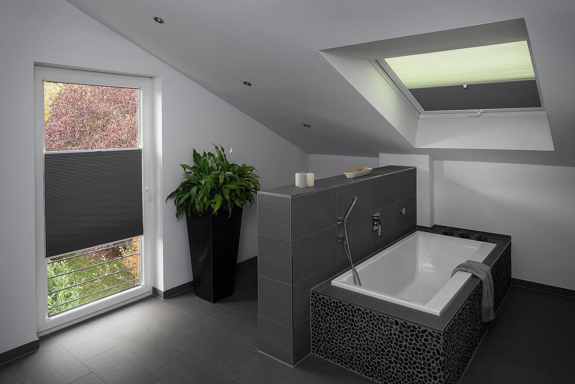 Dachbad mit freistehender Badewanne und MHZ Duette® Wabenplissees an Tür- und Dachfenster in dunklem und hellem Design.