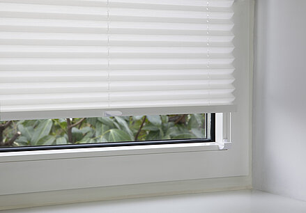 Weisses Plissee mit Glasleistenträgern montiert, verschraubt in der Glasleiste eines Kunststofffensters.