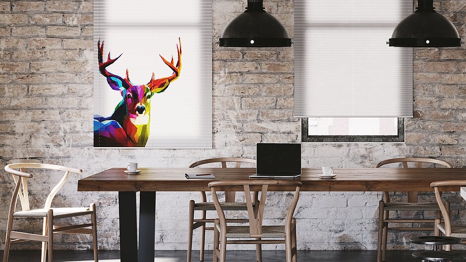 Plissee mit farbigem Hirsch-Digitaldruck in modernem Arbeitsraum mit Backsteinwand und Holztisch.