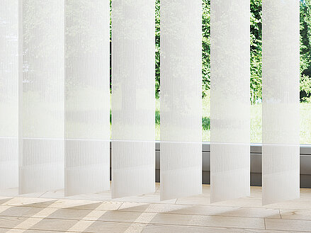 Lasercut-Lamellen „Moxxi“ mit transparenter vertikaler Linienstruktur vor Fenster mit Tageslicht