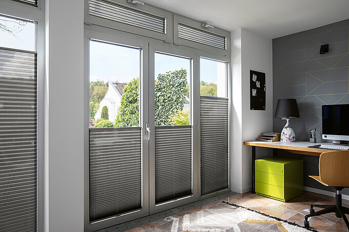 Graue Plissees als Sicht- und Blendschutz in modernem Homeoffice mit Schreibtisch und Oberlichter