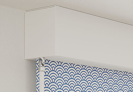 Motorisiertes Kassettenrollo mit weisser Kassette und blau-weiss gemustertem Stoff in Wellenoptik