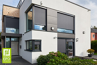 Ein modernes weisses Wohnhaus mit grossflächigen Fenstern, die mit ZIP-Screens als aussenliegender Sonnenschutz ausgestattet sind.