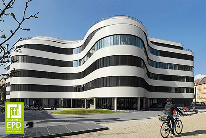 Ein modernes, geschwungenes Bürogebäude mit horizontalen Lamellen an den Fensterfronten als aussenliegender Sonnenschutzsystem von MHZ.