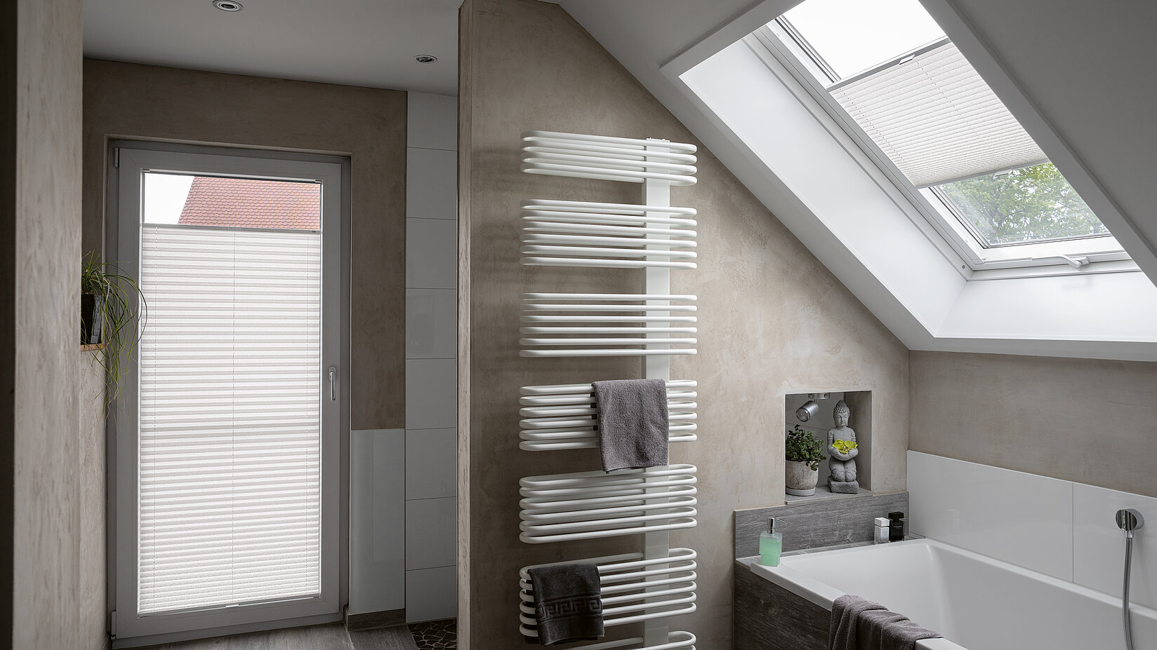 Plissees an Tür und Dachfenster in modernem Bad mit Wanne und schräger Decke.