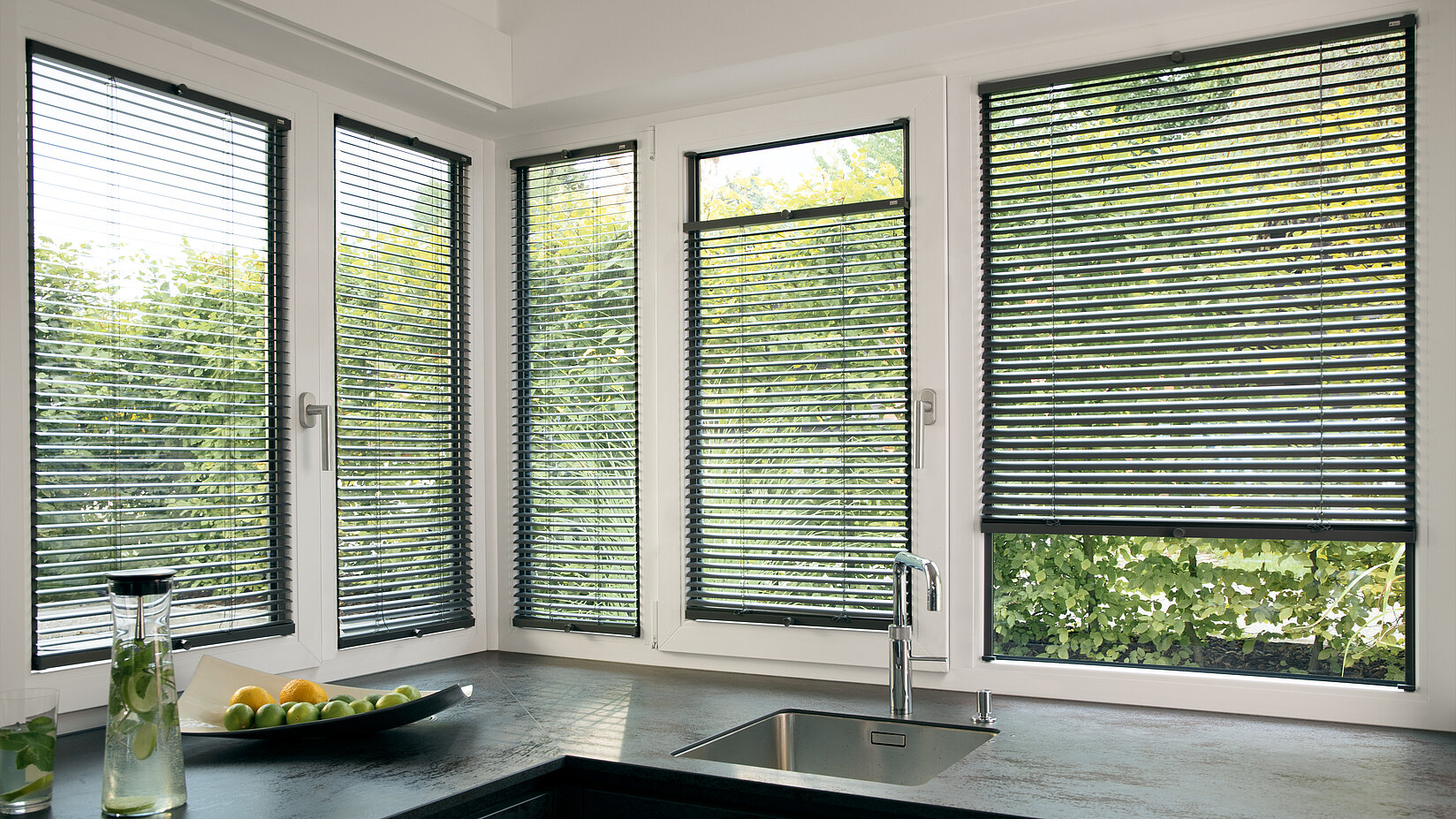 Küche mit Twinline-Jalousien direkt im Fensterrahmen. Dunkle Lamellen schützen vor Blicken und blendendem Licht.