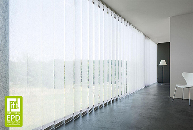 Bodentiefe Fenster mit weissen Vertikaljalousien von MHZ in einem modernen, minimalistisch eingerichteten Raum mit Stuhl und Stehleuchte.