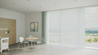 Heller Raum mit Rollwagen, Tischgruppe und weissen Lamellenvorhängen vor grosser Fensterfläche mit Ausblick