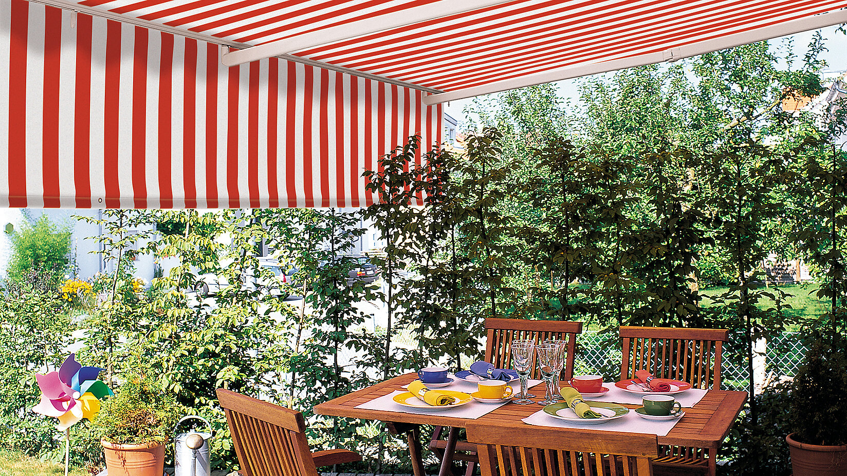 [Translate to Französisch:] rot weiss gestreifte Tragrohrmarkise Classic mit gedecktem Tisch