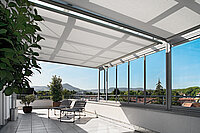 Innenliegende Markisenanlage unter Glasdach einer Dachterrasse mit Aussicht ins Grüne.