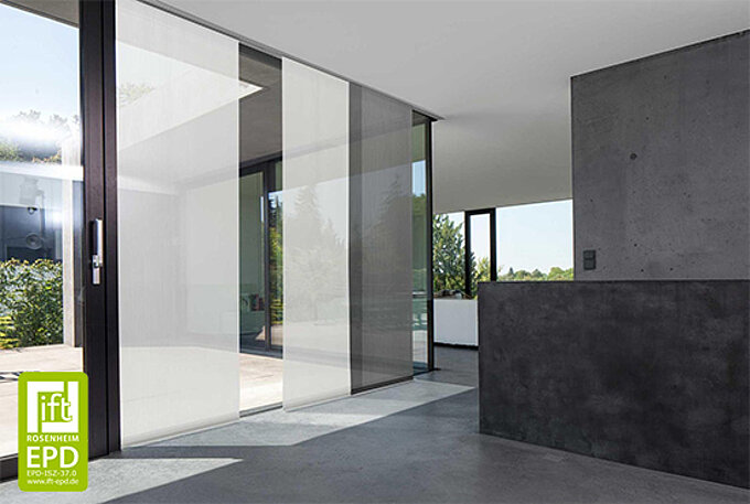 Grosse Glasfront mit halbtransparenten MHZ-Flächenvorhängen in einem modern eingerichteten Wohnbereich mit Sichtbetonelementen.