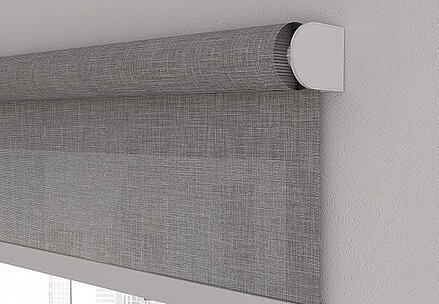 Detailaufnahme eines grauen Rollos mit Strukturstoff und weisser Deckenhalterung