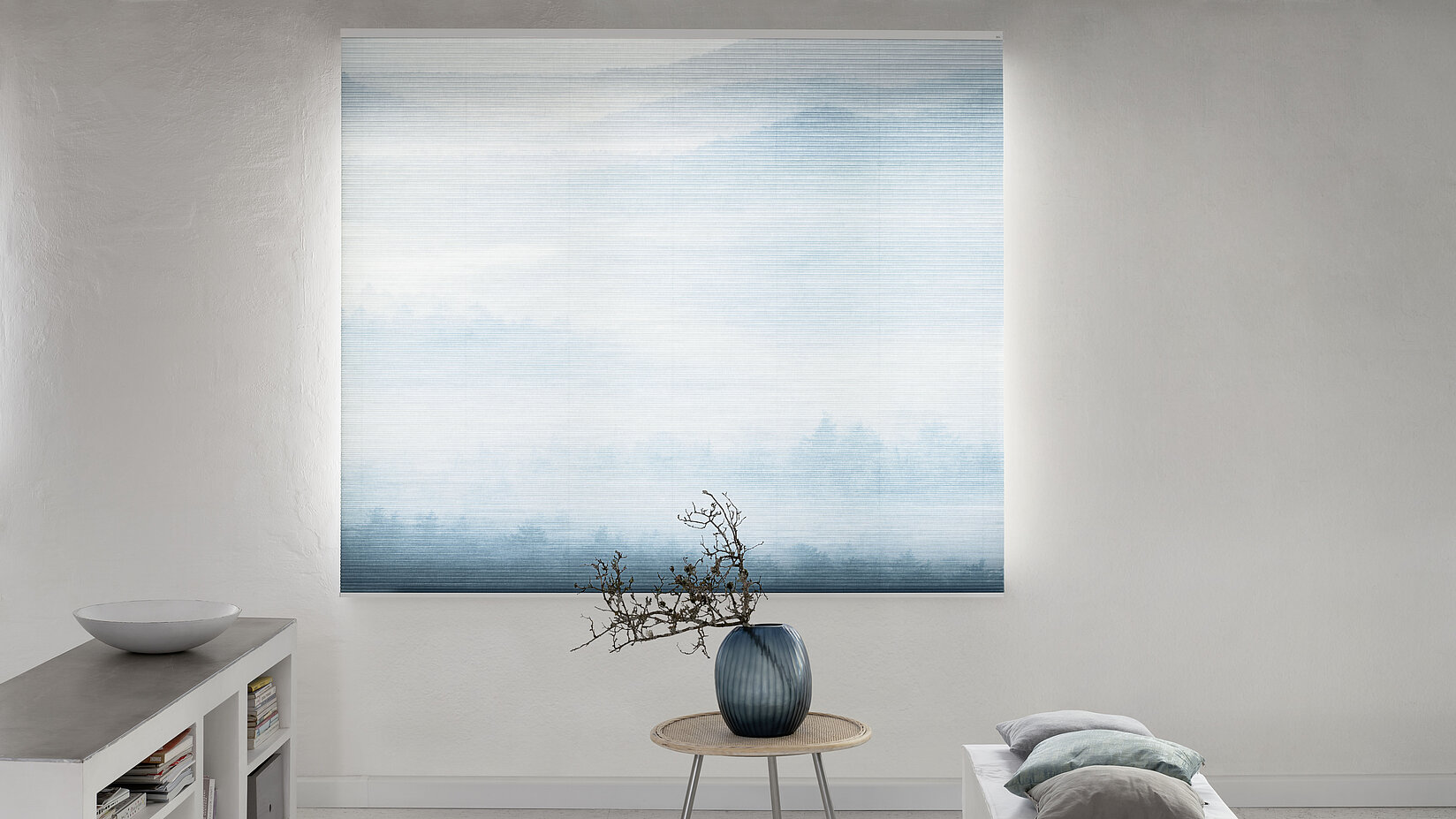 MHZ Wabenplissee mit sanftem Landschaftsmotiv in Blau, vor einem hellen Raum mit minimalistischer Einrichtung.