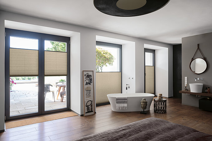 MHZ Plissee Kolja Beige Plissees im unteren Fensterbereich als Sichtschutz in modernem Badezimmer mit freistehender Badewanne.